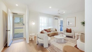 Una sala de estar moderna con un sofá, sillones, una mesa de centro y una mesita auxiliar.