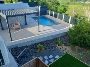 Un espace piscine aménagé sur le toit, avec une pergola, des sièges et une vue sur le paysage environnant.