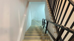 A staircase with black railings and yellow edge strips, leading to a landing with a light-colored wall. - SJ Beach House Patong (Patong)
