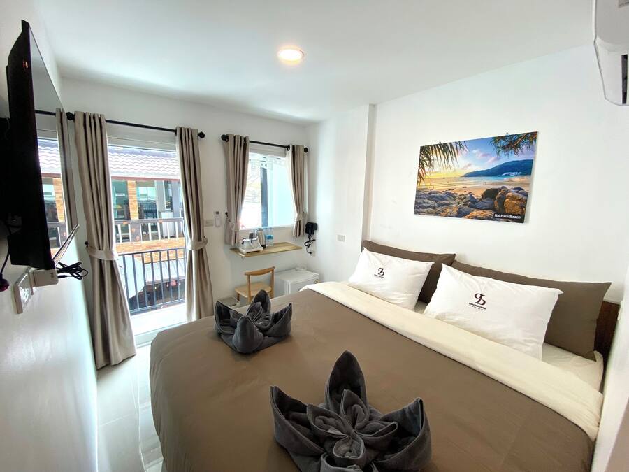 Hotelkamer met een groot bed, een flatscreen televisie aan de muur, een klein tafeltje met een lamp en een raam met gordijnen.