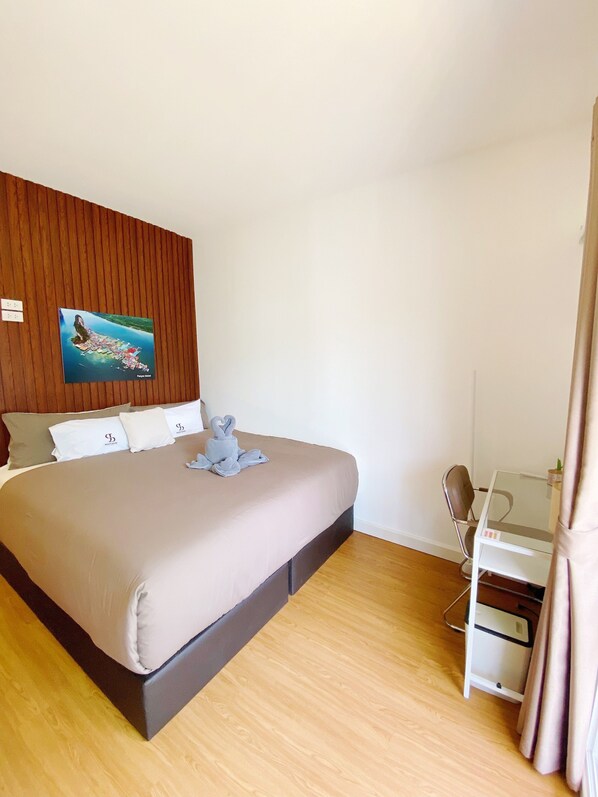 A bedroom with a bed, a desk, and a wall-mounted picture. - SJ Beach House Patong (Patong)