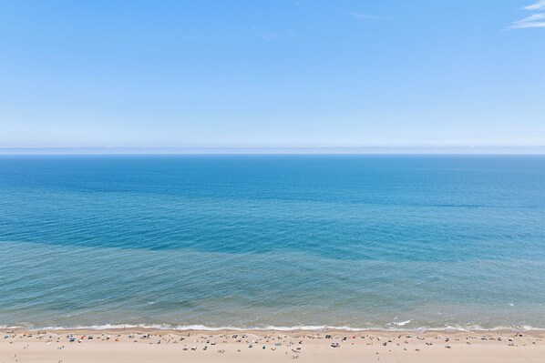A beach with clear blue water and a sandy shore. - Villas White Buildings in North Ocean City, with a pool and close to the beach (Ocean City)