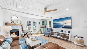 A modern living room with a fireplace, leather sofas, a coffee table, and a large painting of a beach scene.