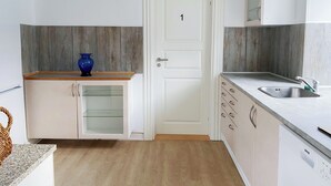 Cocina compacta con encimera de madera, lavaplatos integrado y una puerta con el número 1.