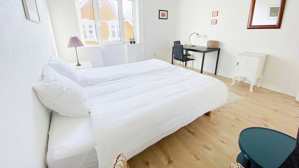 Un dormitorio con una cama grande, un escritorio, una silla y una mesita.