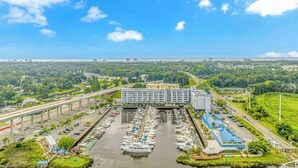 Luchtbeeld van een jachthaven met boten, een groot hotelgebouw en een viaduct.