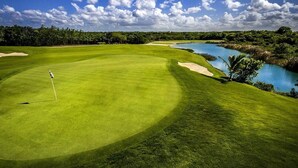 Campo de golf con un mástil de bandera, bunkers de arena y una masa de agua.