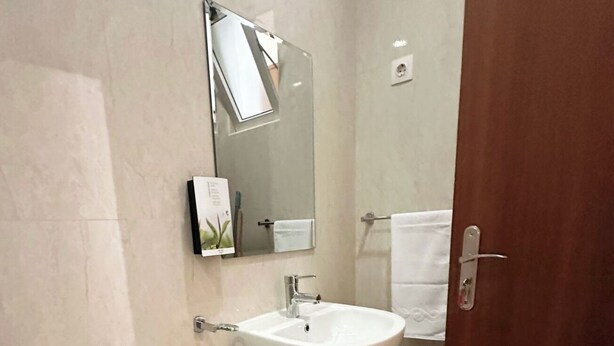 A modern bathroom with a toilet, sink, and mirror. - Flat in Praia Plateau (Praia)