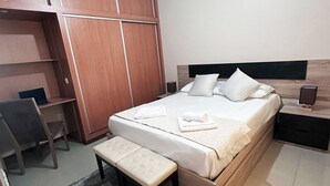 A bedroom with a bed, bench, desk, and wardrobe. - Flat in Praia Plateau (Praia)