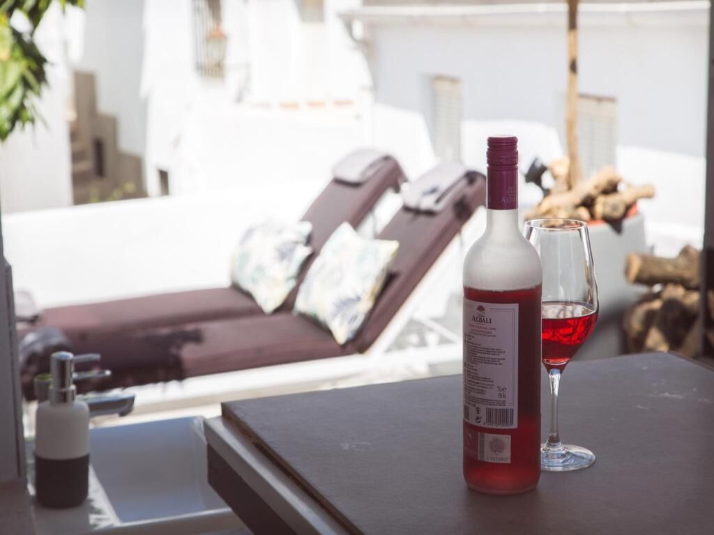 Una botella de vino tinto y una copa sobre una mesa, con vistas a un área de estar.