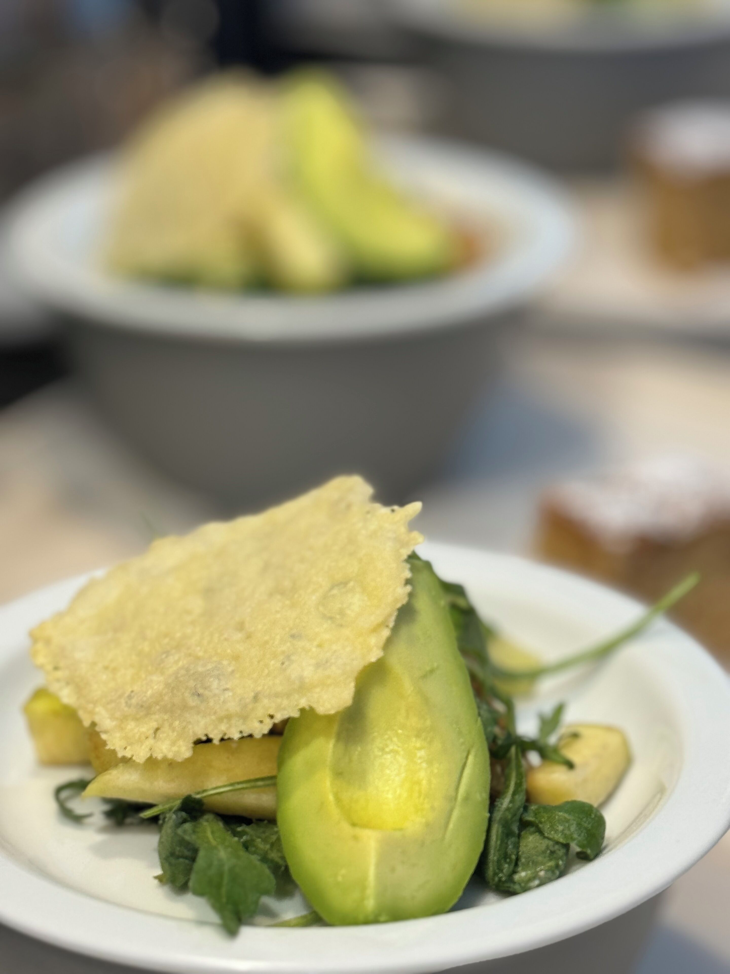 A plate with a piece of bread, avocado, and greens.