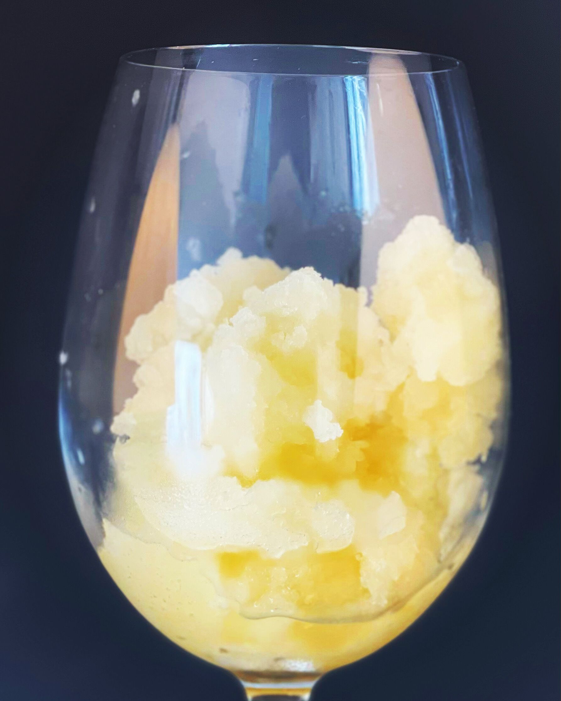 A glass containing a yellowish substance, possibly a dessert or beverage.