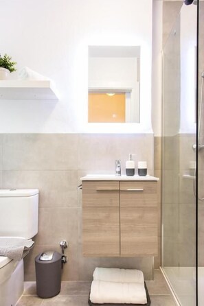 A modern bathroom with a toilet, sink, vanity, and shower. - Almijara Residence (Cómpeta)