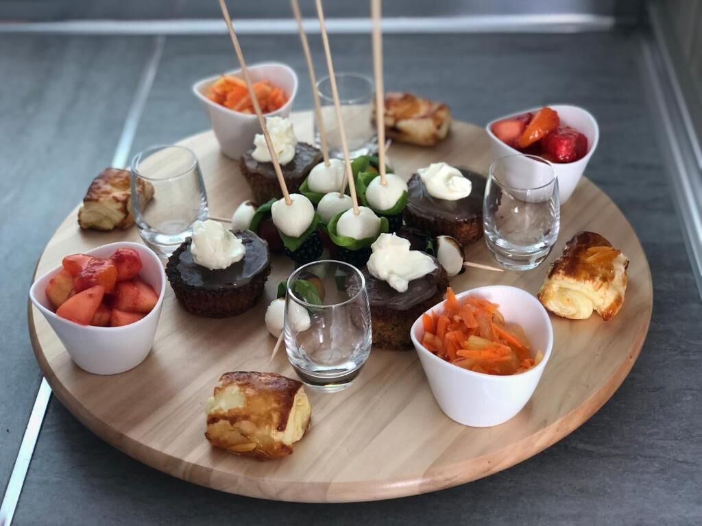A wooden board with various food items and small glasses of water.