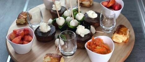 A wooden board with various food items and small glasses of water.