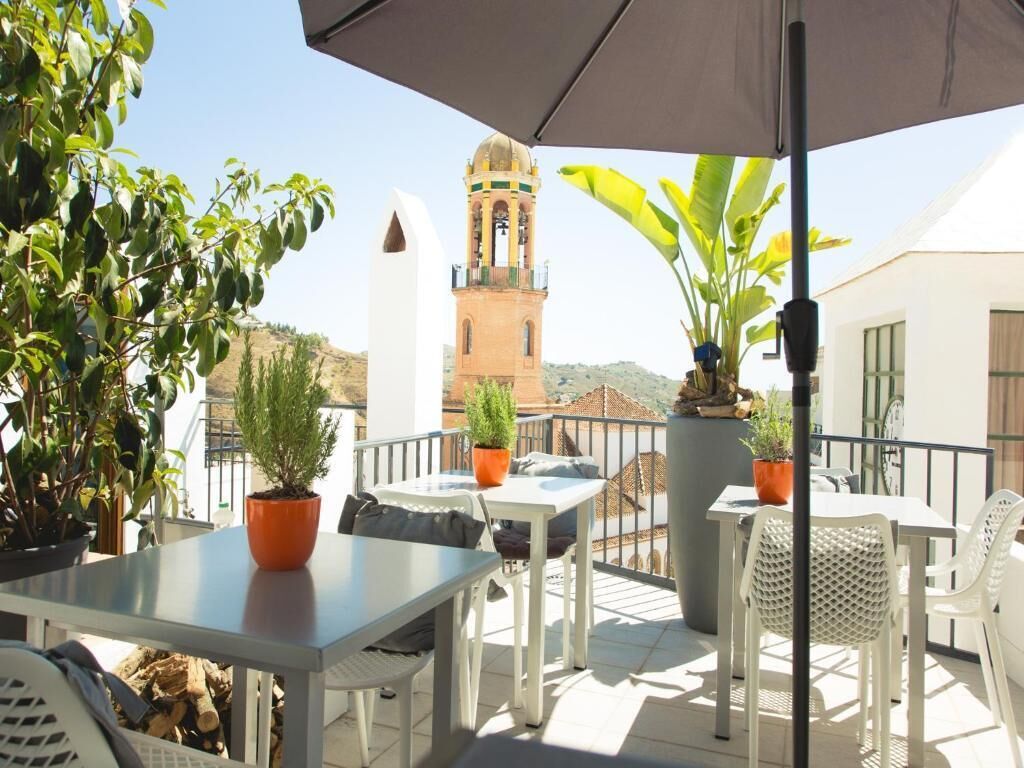 A terrace with outdoor seating, potted plants, and a view of a tower.