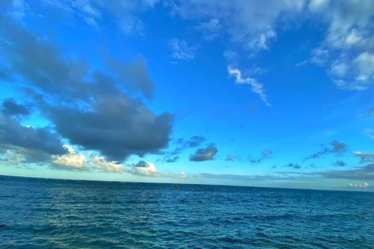 Vista do oceano com céu limpo e algumas nuvens.