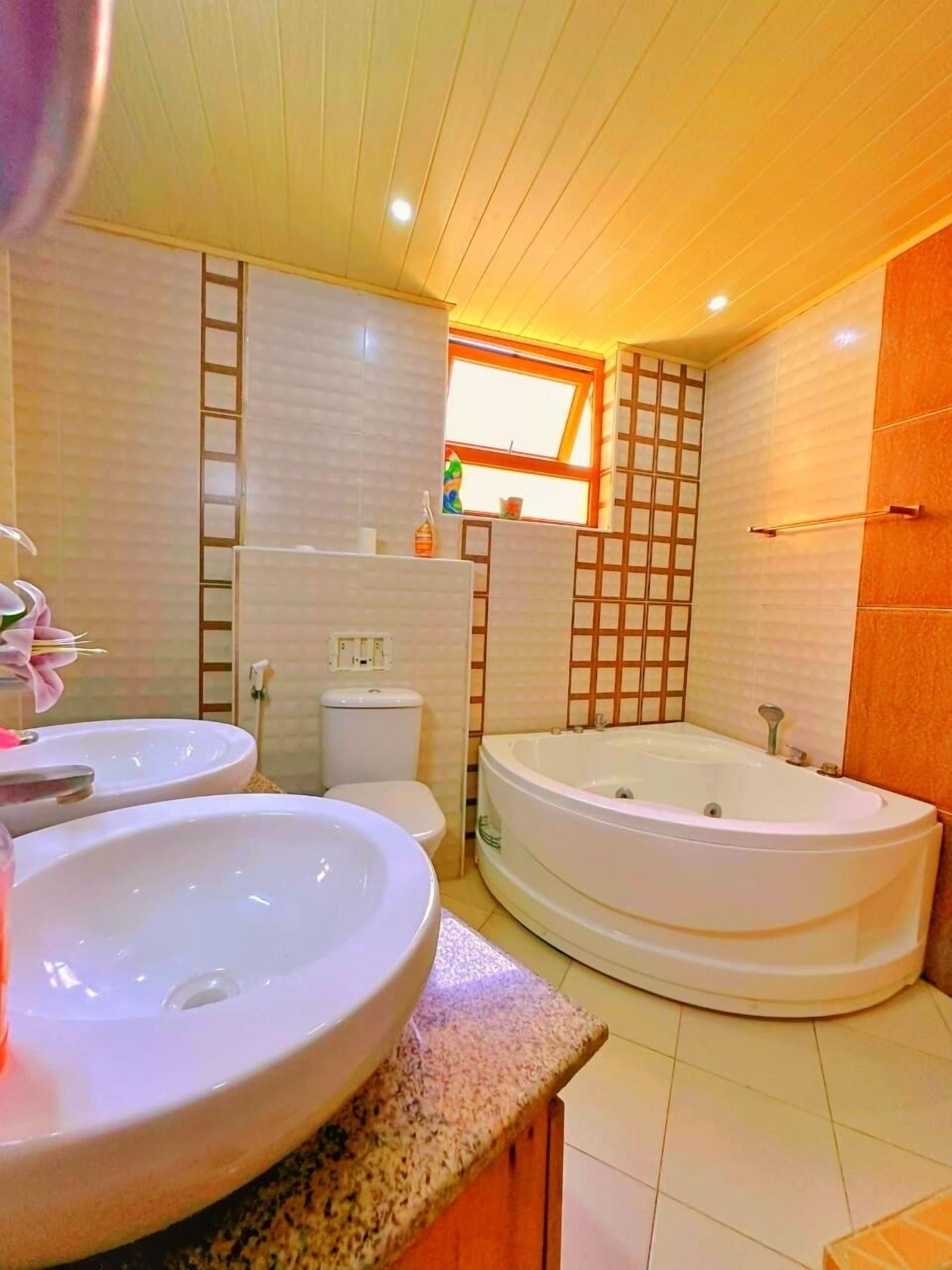 Un baño con dos lavamanos, un inodoro y una bañera grande.