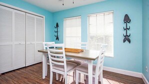 Un coin repas comprenant une table et des chaises, un ventilateur de plafond et une fenêtre avec des stores.