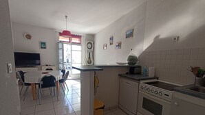 A compact kitchen with a stove, sink, and dining area. - 3-bedroom house, sleeps 6, near station, Sète, WIFI (Sète)