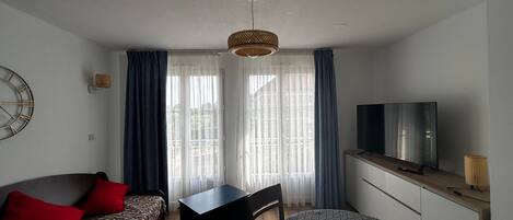 A compact room with a bed, a sofa, a desk, and a TV.