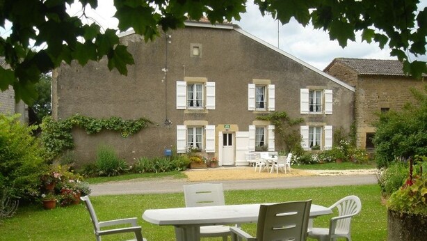 Een gebouw met een tuin en een terras met een tafel en stoelen.
