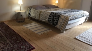 Een slaapkamer met een bed, twee bedlampen, een radiator en een kamerkleed met een patroon.