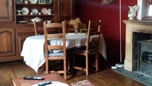 Een eetruimte met een houten tafel en stoelen, een kast met servies en een open haard.