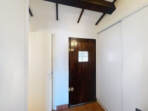 Stylish hallway with a door at the end, featuring a small window and a door on the left.