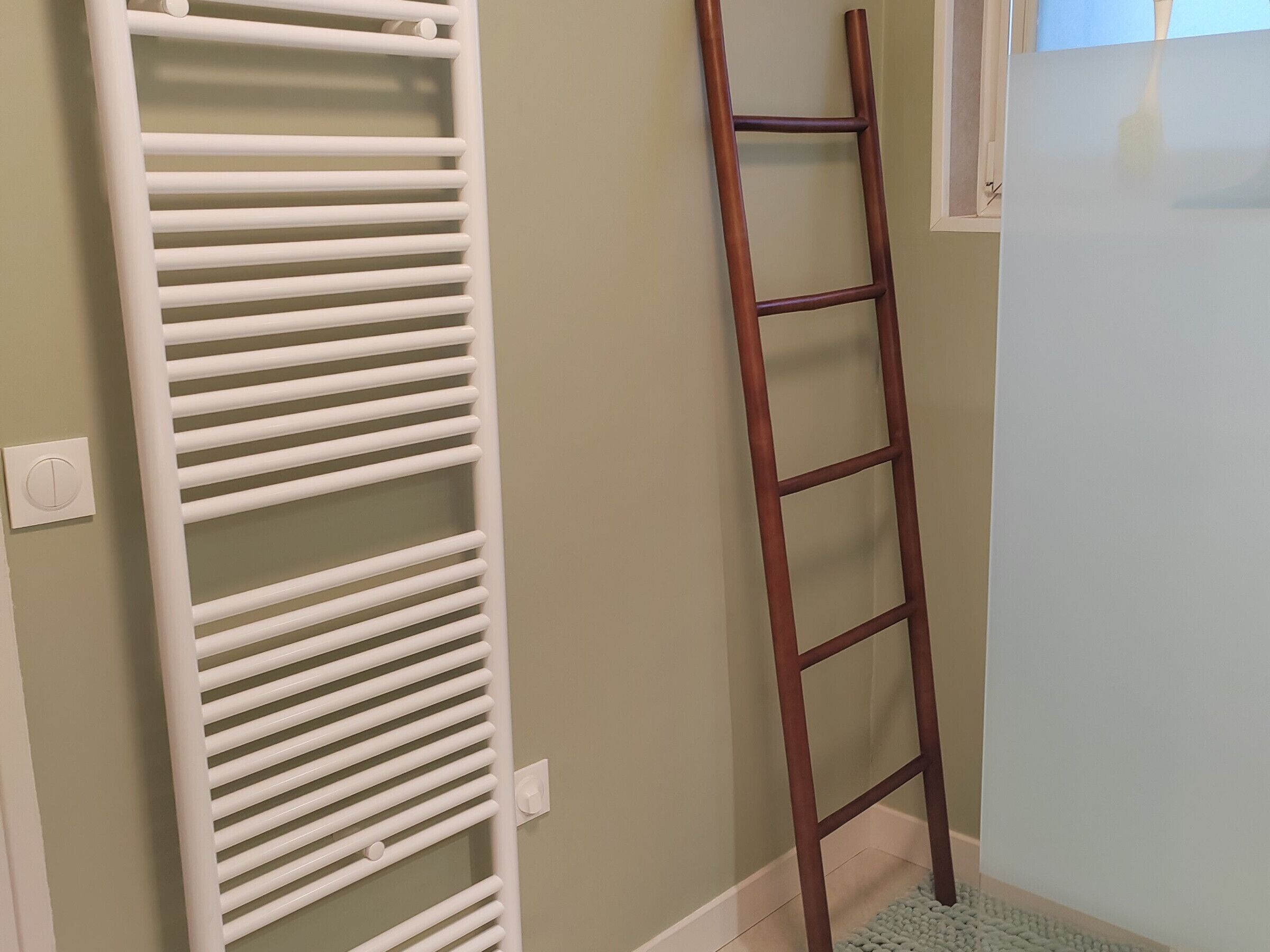 A white radiator, a wooden ladder, and a light blue wall.