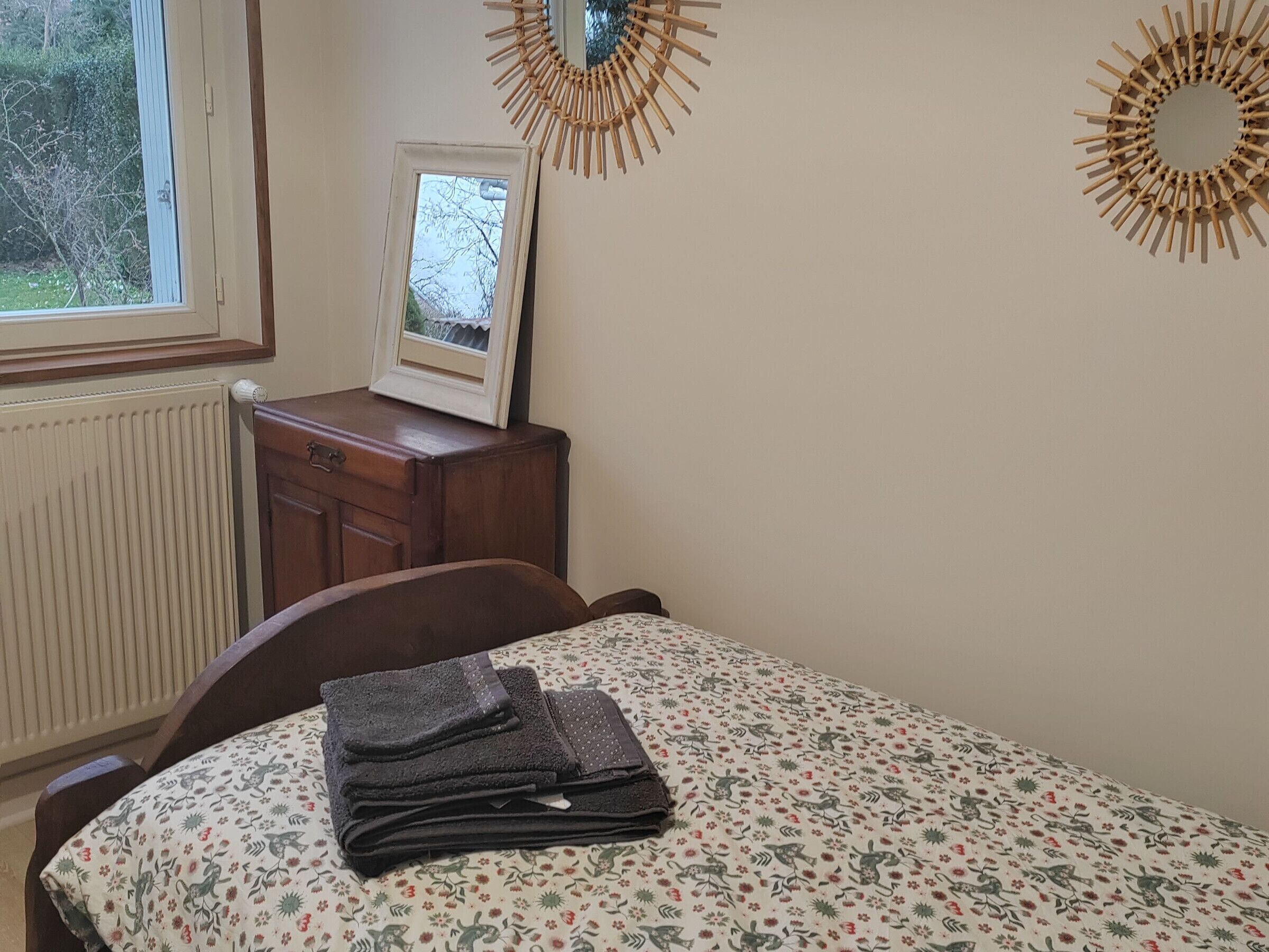 A bedroom with a bed, a dresser, a mirror, and a window.
