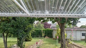 A garden with a pergola structure, a stone bench, and various plants and flowers. - House with enclosed garden in Villabon (Villabon)
