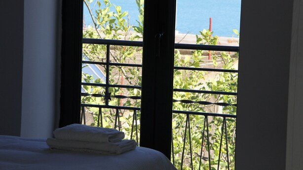 Une chambre d’hôtel avec un lit et une fenêtre donnant sur une étendue d’eau et un paysage verdoyant.