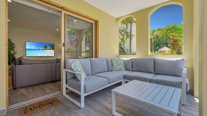 A modern living room with a grey sectional sofa, a white coffee table, and a television on the left. - Makai Hawaiian for direction towards the ocean (Mount Coolum)