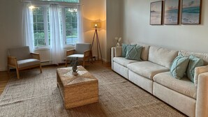 A living room with a large arched window, a sofa, two armchairs, a floor lamp, and a coffee table.
