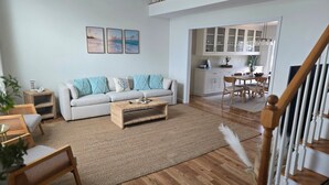 A spacious living room with a sofa, coffee table, and a view into the kitchen.