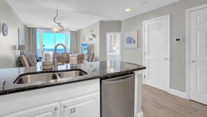 A modern kitchen with a granite countertop, stainless steel sink, and a built-in dishwasher.