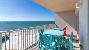 A balcony with turquoise chairs and a table, overlooking a beach and the ocean. - Seawind 902 by Liquid Life (Gulf Shores)