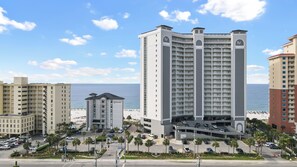 Un hôtel de grande hauteur doté de nombreux balcons, d’un parking souterrain et offrant une vue sur la plage.