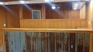 Un intérieur rustique en bois, avec un comptoir en métal, un sol carrelé et un ventilateur de plafond.