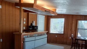 Une pièce compacte comprenant un banc en bois, une petite kitchenette, un canapé-lit et une table à manger avec des chaises.