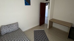 Un dormitori amb un llit, una panxa, un tapet i una porta que dona a una altra habitació.