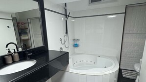 Un bany modern amb un lavabo de superfície negra, un mirall gran, una banyera blanca i una catifa amb ratlles al terra.