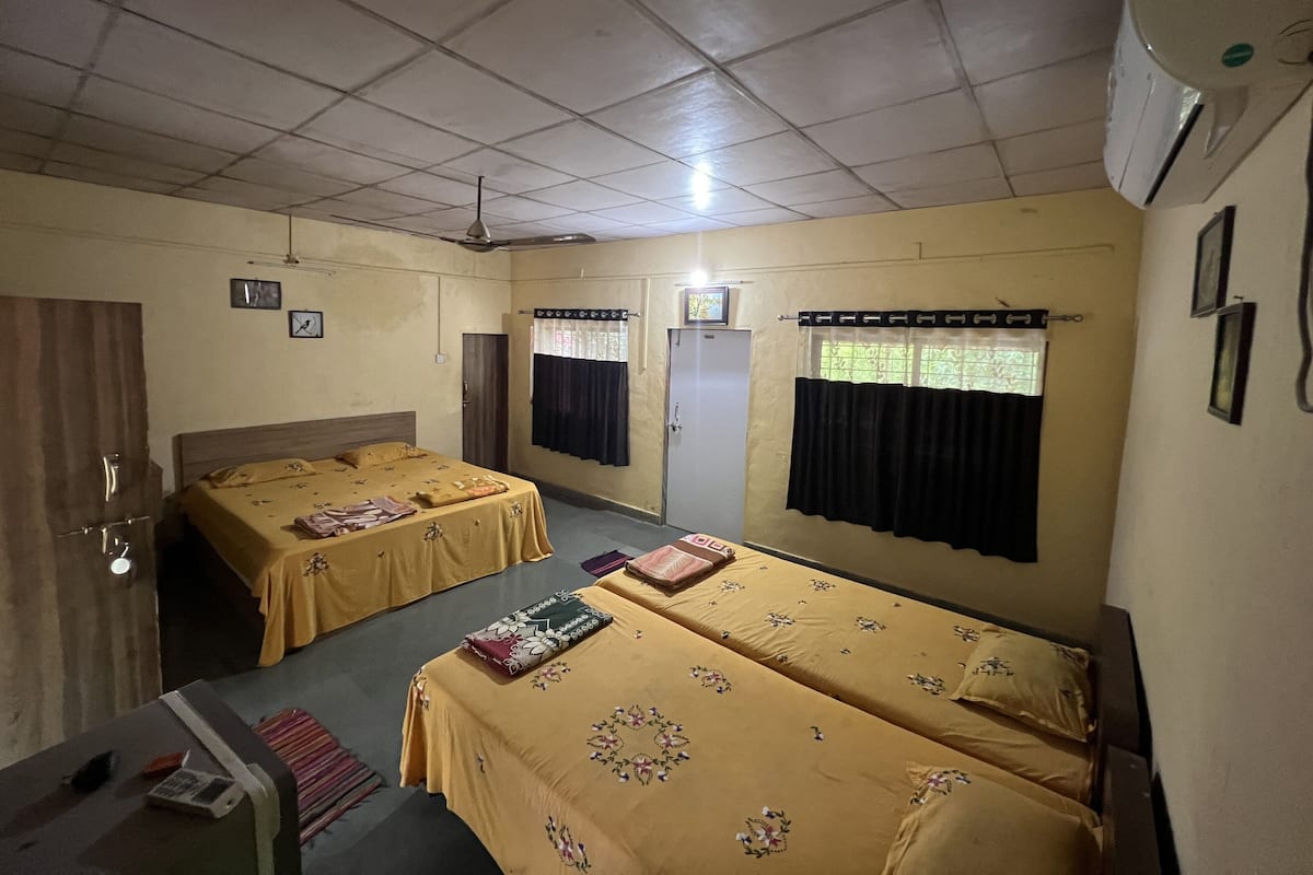 Une chambre d’hôtel avec deux lits, une armoire, un bureau et un ventilateur de plafond.