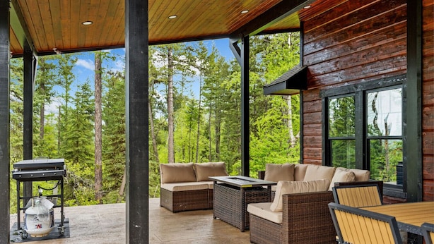 A covered outdoor seating area with wicker furniture and a grill.