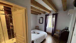 Une chambre avec un plafond en bois, un lit, une chaise, un bureau et une fenêtre avec des rideaux.