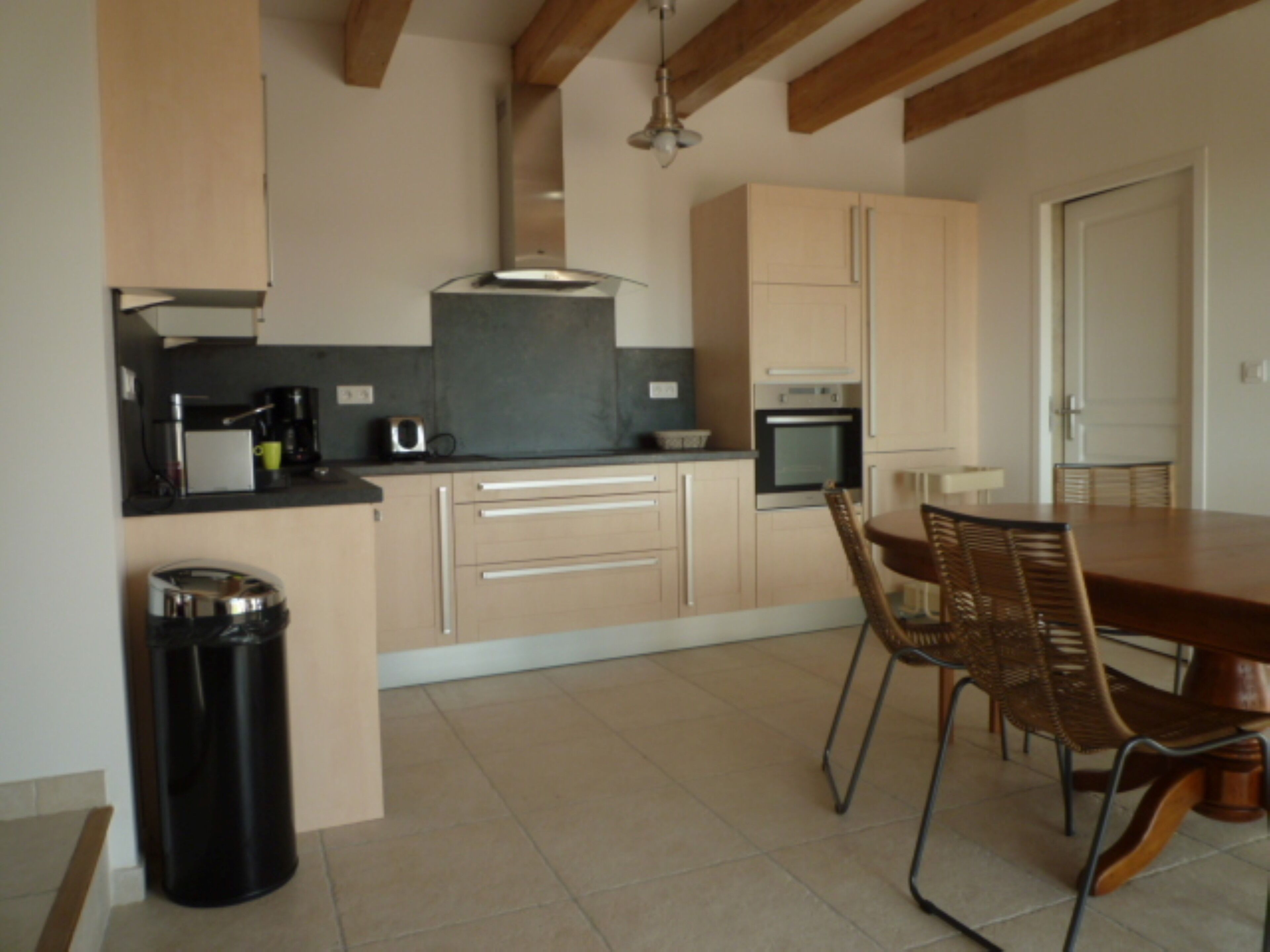A modern kitchen with wooden cabinets, a dining table, and chairs.