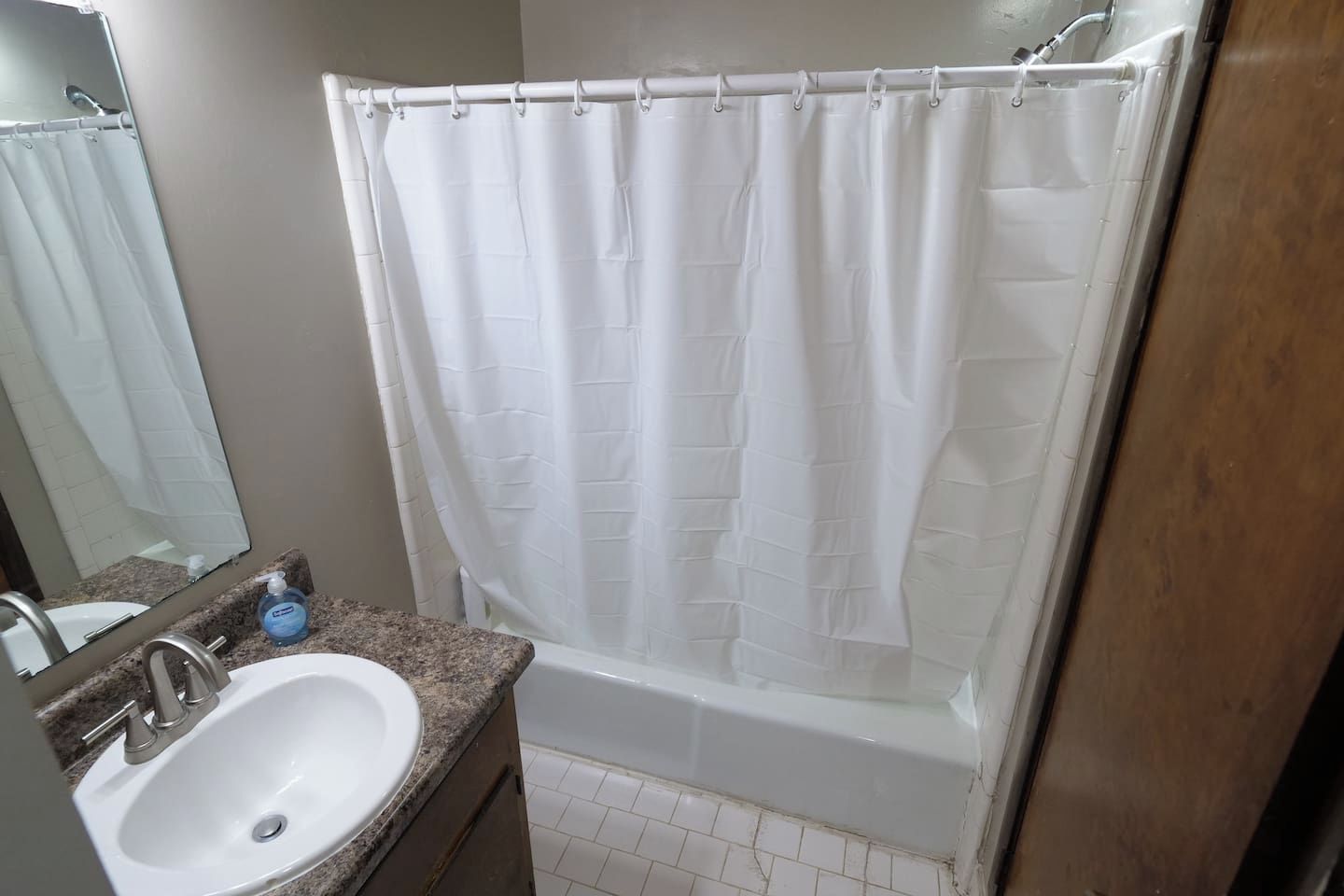 Ein Badezimmer mit einer weißen Badewanne, einem Waschbecken mit Spiegel und einer Duschvorhang.