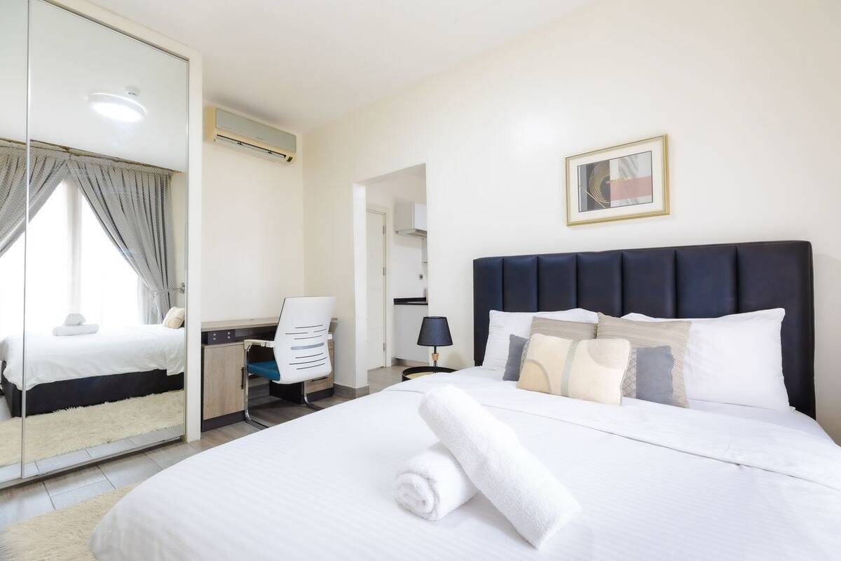 Une chambre d’hôtel avec un lit, un bureau, une chaise, un miroir et un tableau au mur.