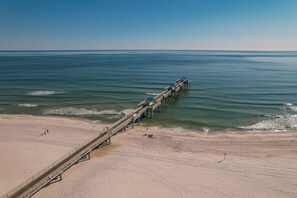 A beach with a wooden pier extending into the ocean.